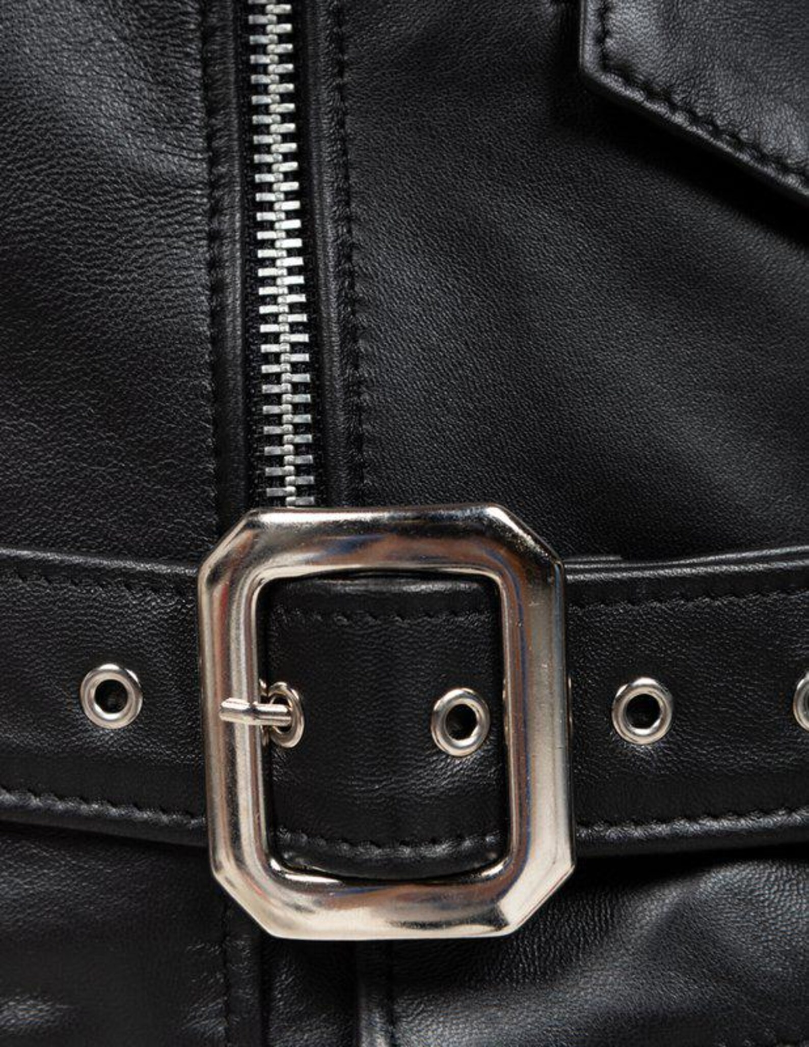 Close-up of a black leather jacket with a silver buckle and zipper.