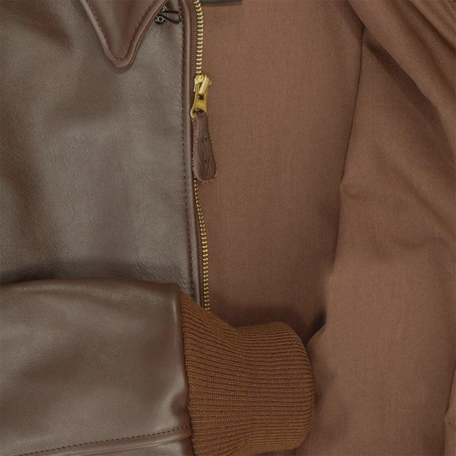 Close-up of a brown leather jacket with a zipper