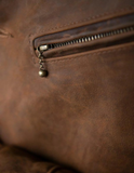 Close-up of a brown leather bag with a zipper