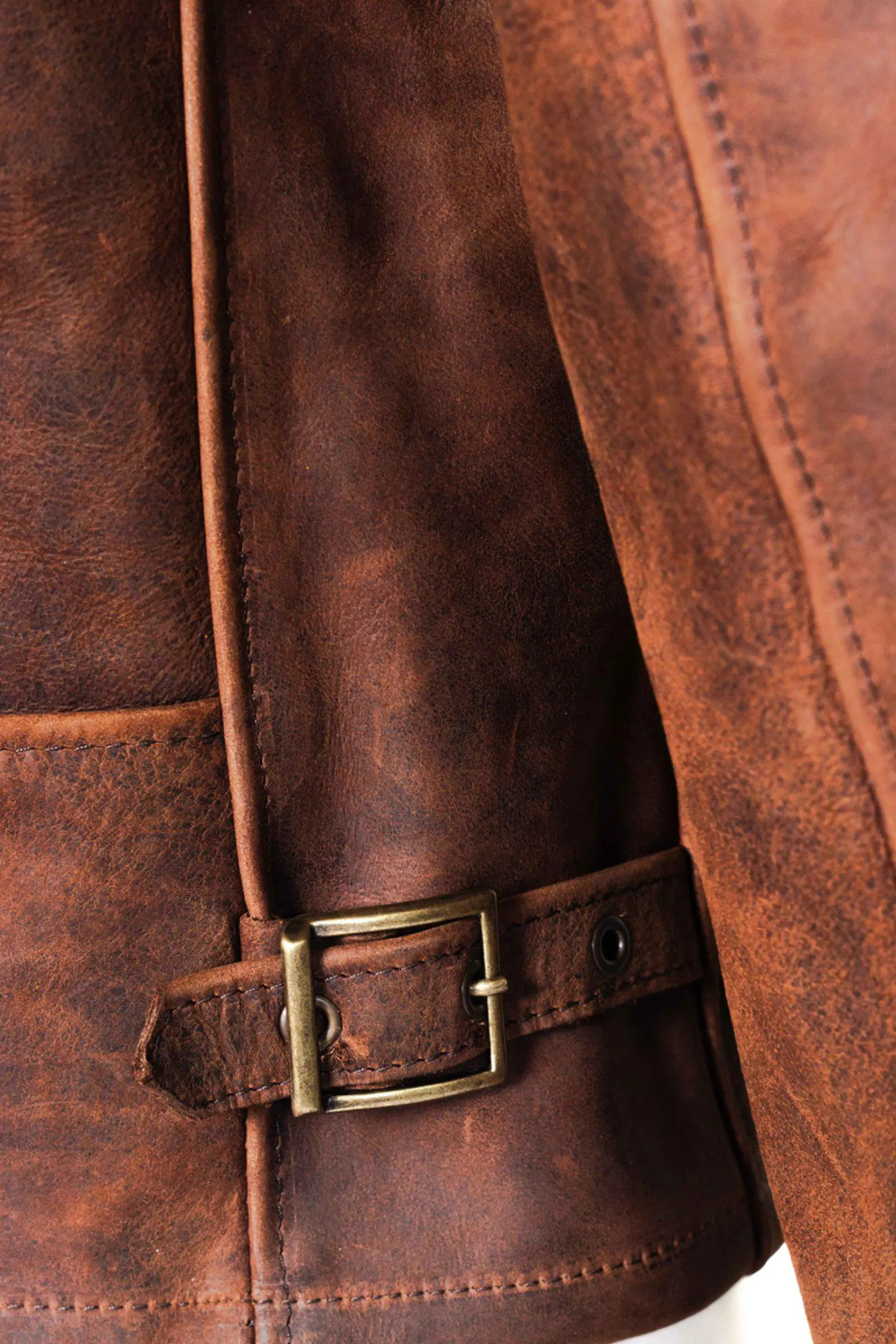 Close-up of a brown leather jacket with a belt buckle.