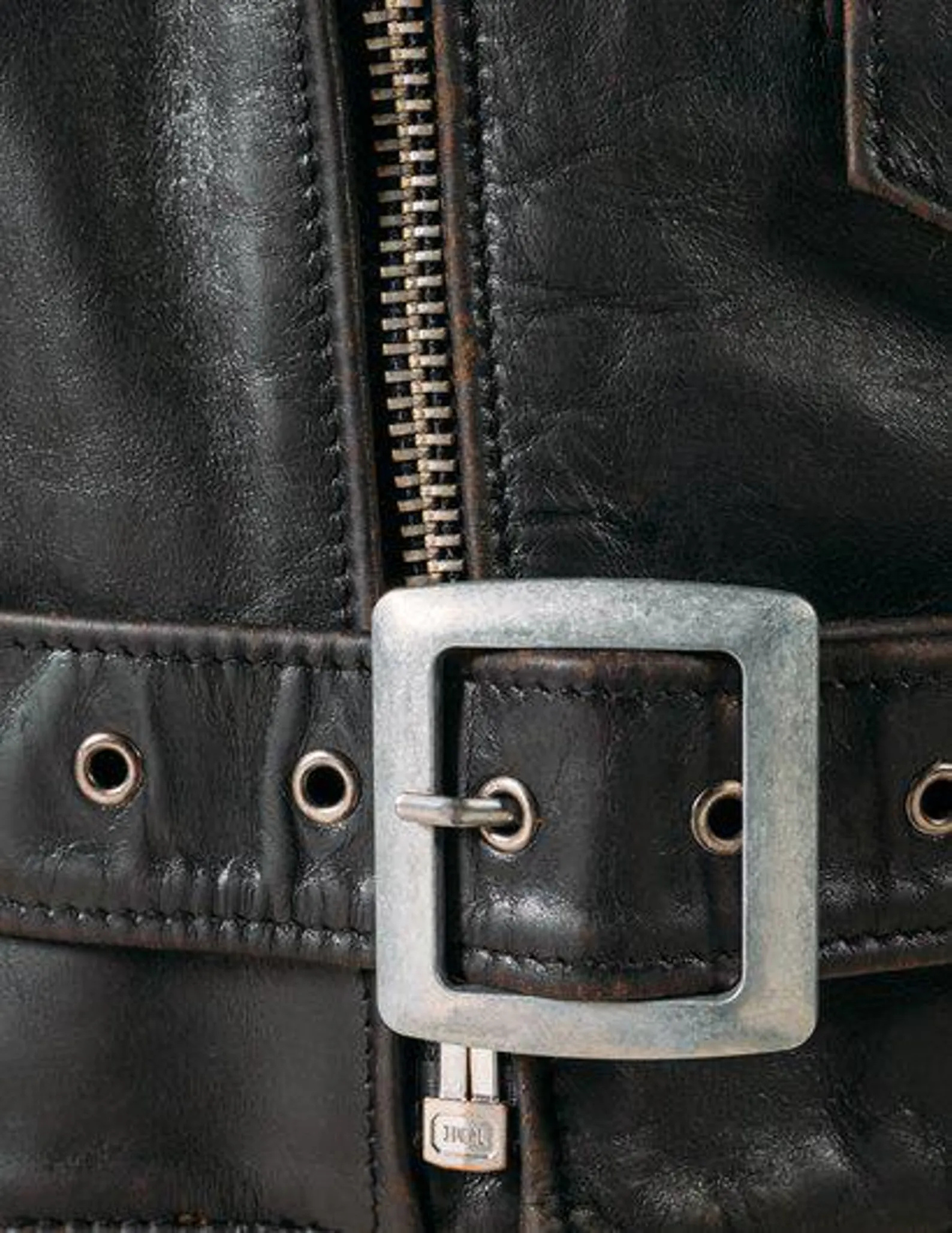 Close-up of a black leather jacket with a silver buckle and zipper.