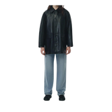 Person wearing a black leather coat and light blue pants