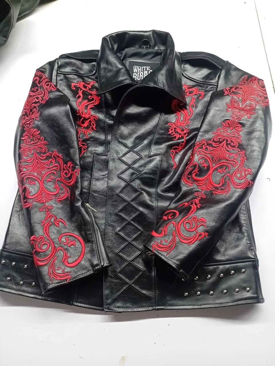 Black leather jacket with red embroidered sleeves, collar folded down