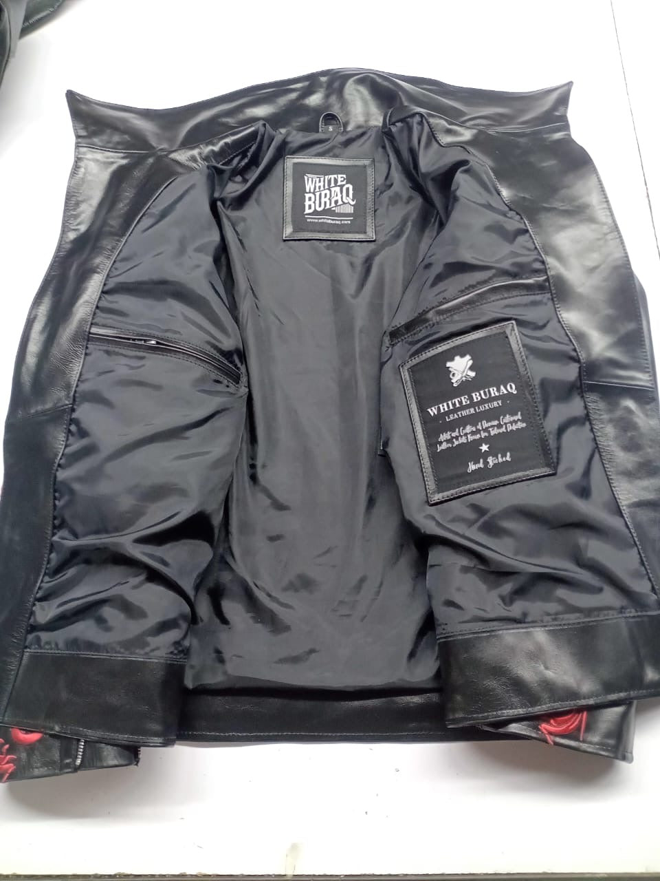 Black satin-finish lining with two inner zip pockets and White Buraq labels