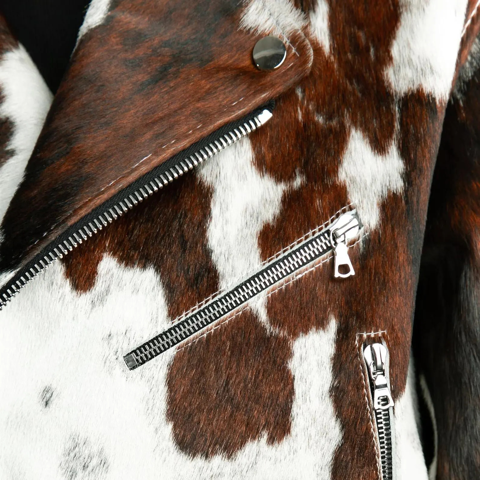 Close-up of a brown and white cowhide leather jacket with zippers.