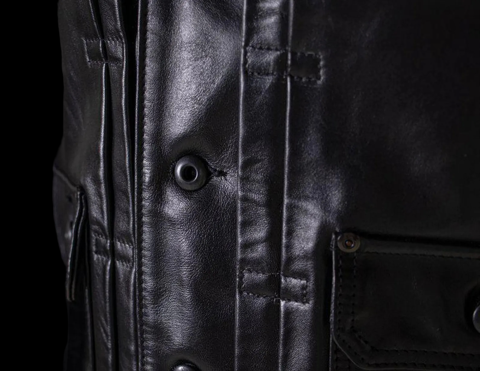 Close-up of a black leather jacket with buttons and stitching details.