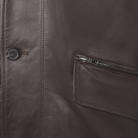 Close-up of a brown leather jacket with a button and zipper pocket.