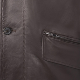 Close-up of a brown leather jacket with a button and zipper pocket.
