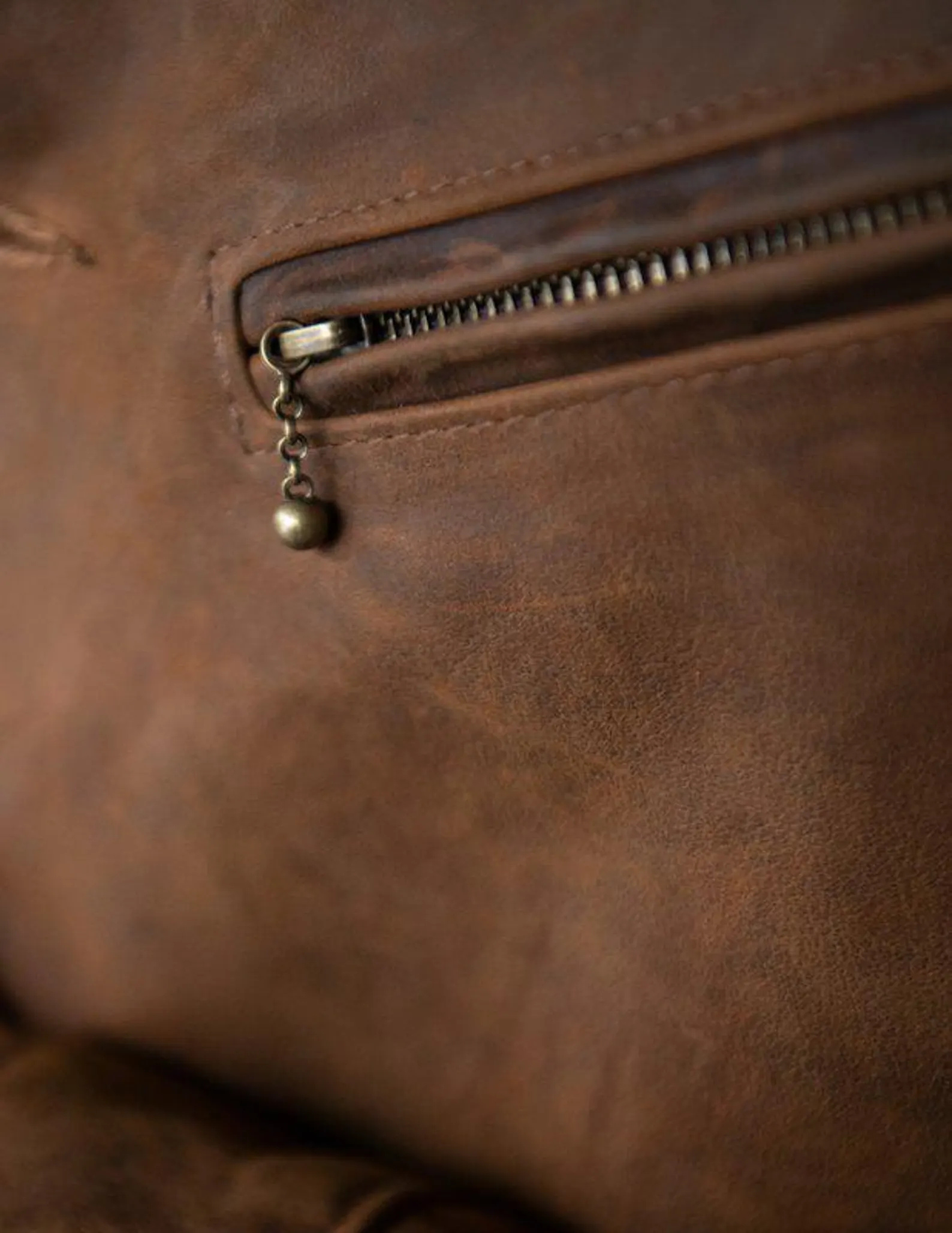 Close-up of a brown leather bag with a zipper