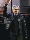 Man in a shiny black jacket waving on a stage