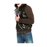 Person wearing a brown hoodie with a shiny black vest over it 