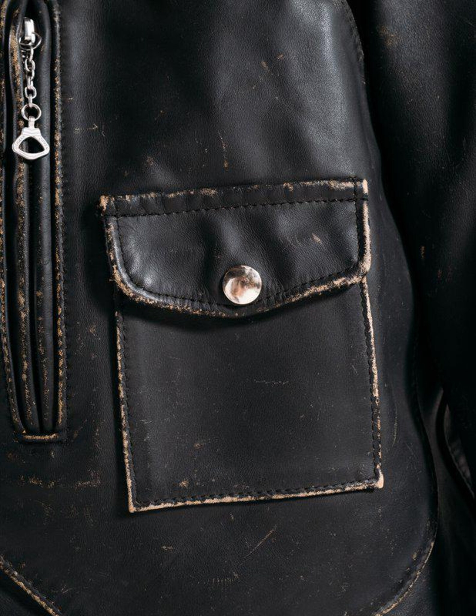 Close-up of a black leather jacket with a buttoned pocket.