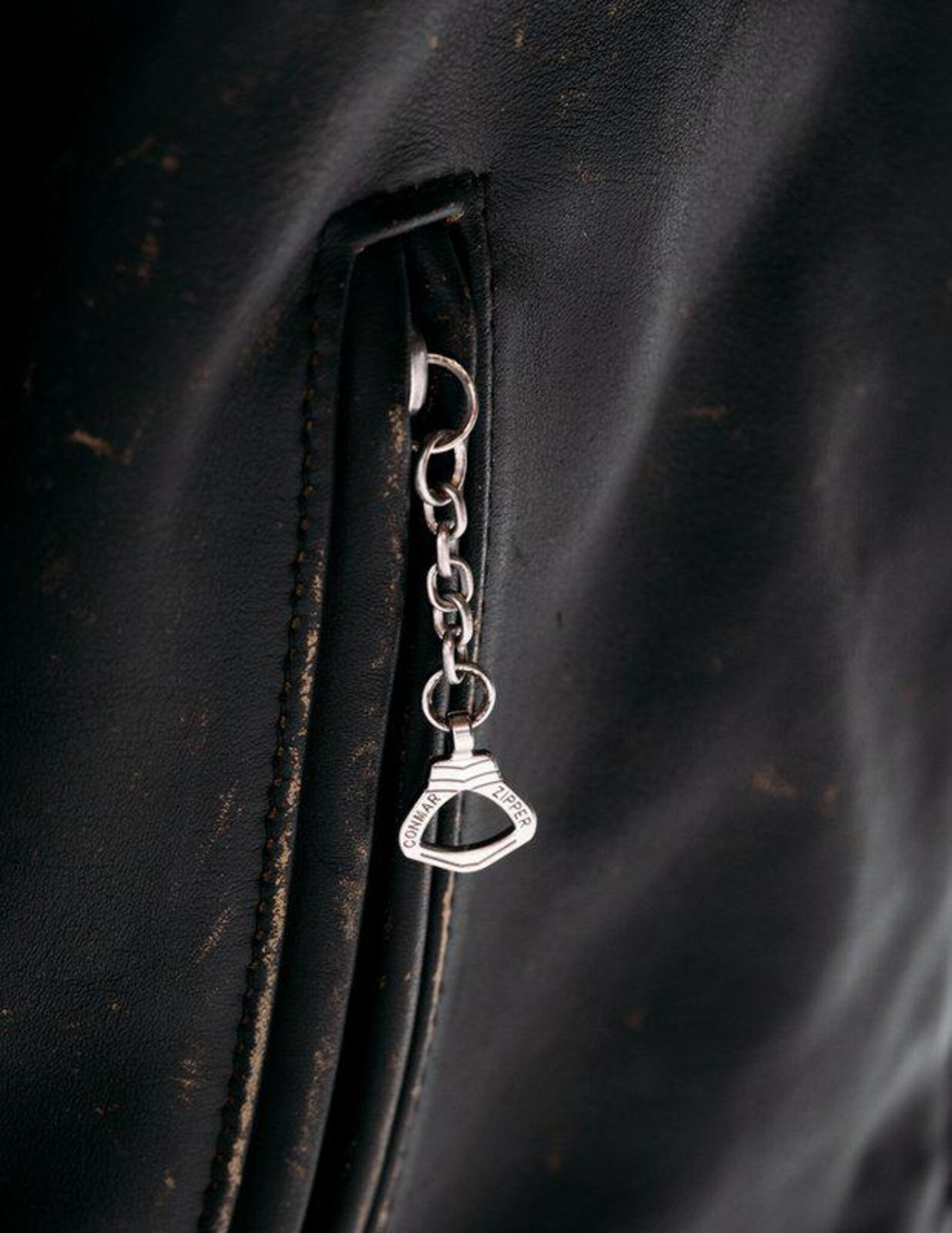 Silver keychain attached to a dark leather surface