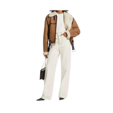 Person wearing a brown jacket with sheer panels, white top, and white pants 