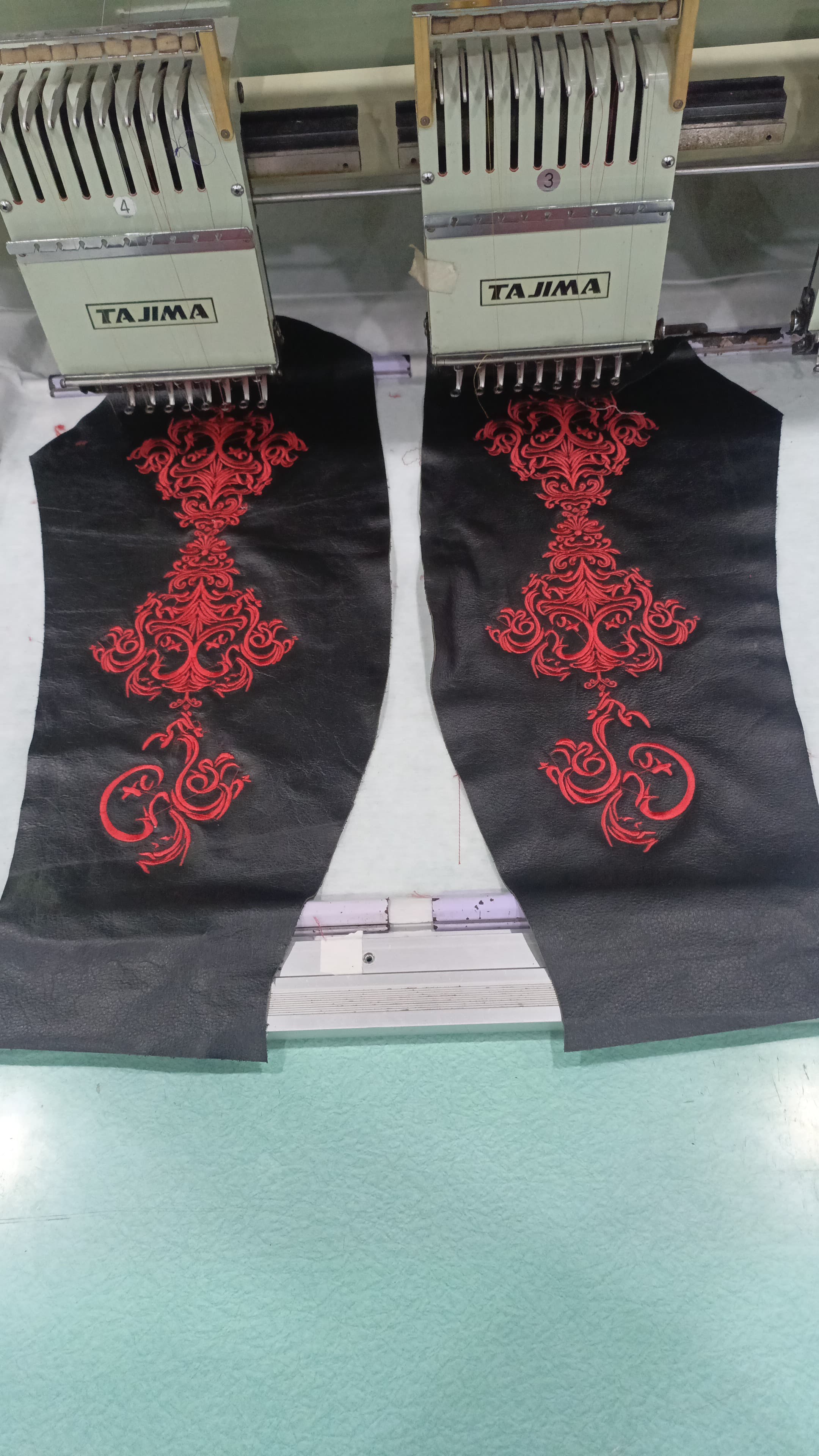 Leather sleeve panels being embroidered in red on a Tajima embroidery machine